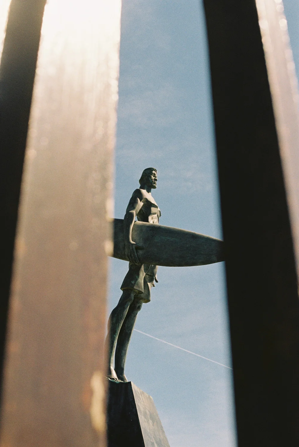 Bronze surfer sculpture framed by weathered steel